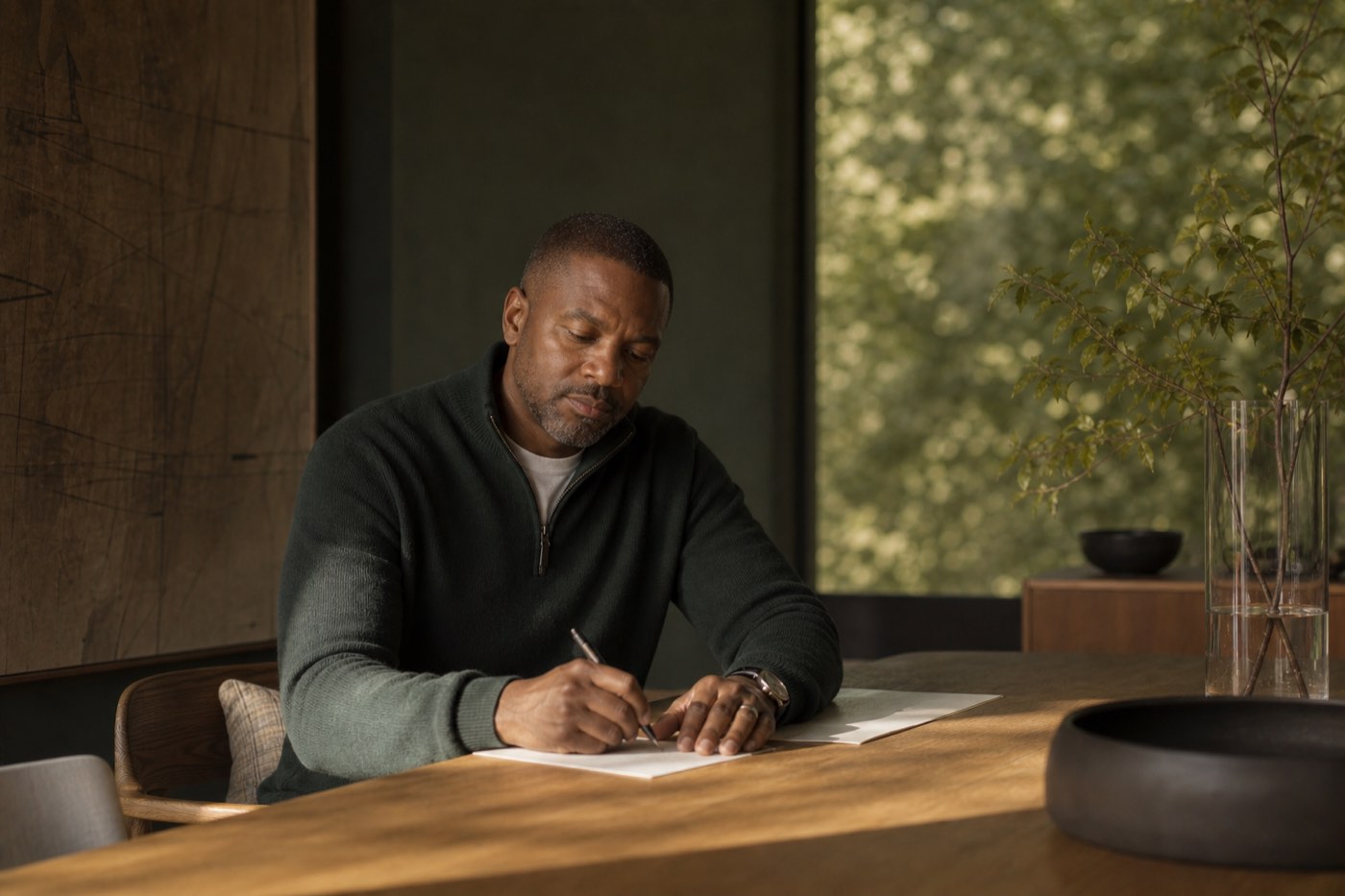 Daniel Okafor writing beside a window in a quiet Oakland room