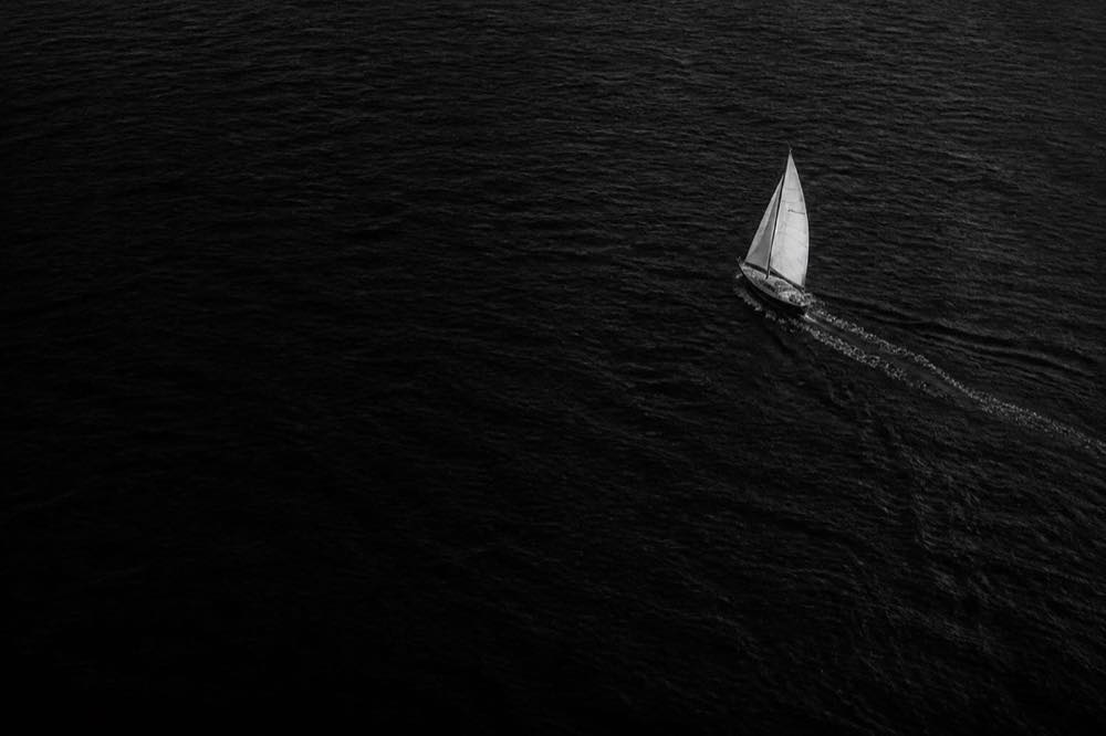 A single sailboat crossing dark open water